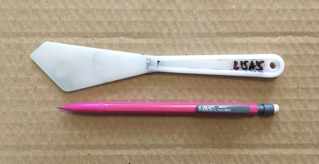 Photo of white plastic spatula and pink retractable pencil.